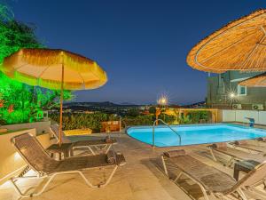 a swimming pool with two umbrellas and two chairs and a swimming poolvisor at Holiday Sea View Villas in Katastárion