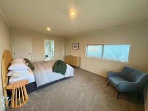 a bedroom with a bed and a blue chair at Mountain Views on the Reserve in Wanaka +10 photos