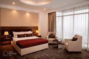 a hotel room with a bed and a chair at Crown Comfortia Hotel Jashore in Jessore