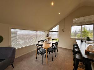 a dining room with a table and chairs and windows at Mountain Views on the Reserve in Wanaka