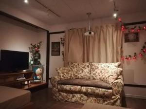 a living room with a couch and a television at Hitsujipotchi-Kyoto in Yatsuai