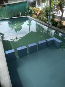 a swimming pool with three chairs and a table at Kuttickattil Gardens Homestay in Kottayam