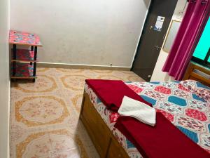 a bedroom with a bed with red sheets and a floor at SH Guest House Malvan in Malvan +2 photos