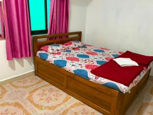 a bed in a bedroom with pink curtains at SH Guest House Malvan in Malvan