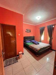 a bedroom with red walls and a bed and a door at Villa Pondok Aurora in Campaka
