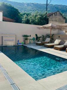 a swimming pool with an umbrella and some chairs at Anestis Studios in Lidia