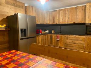 eine Küche mit Holzschränken und einem Edelstahlkühlschrank in der Unterkunft Angel Chalet in Serina