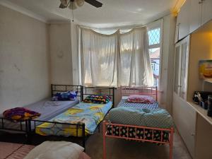 two twin beds in a room with a window at Wembley Stadium Room with Parking and Breakfast in London