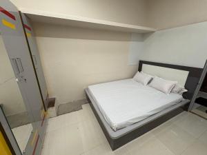 a small room with a bed with white sheets and pillows at vMAC in Thiruchendur