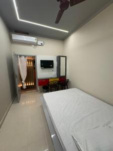 a bedroom with a white bed and a television at vMAC in Thiruchendur