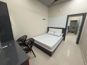 a small bedroom with a bed and two chairs at vMAC in Thiruchendur