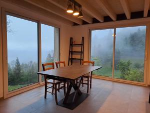 a dining room with a table and chairs and windows at La remise de Saussenigoutte in Cornimont