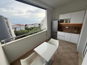 a white kitchen with a large window and a white table at Apartmants Šestić in Tučepi