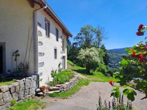 a house with a stone wall next to a building at La remise de Saussenigoutte in Cornimont