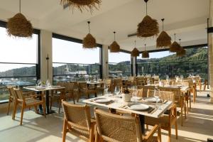 a restaurant with tables and chairs and large windows at Lithari Luxury Villas in Agios Georgios
