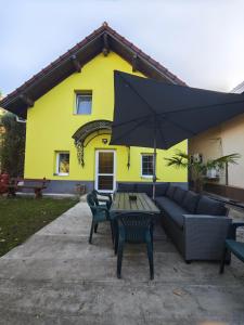 a yellow house with a couch and an umbrella at Pensiunea Sofia in Băţălar