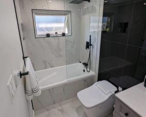 a bathroom with a tub and a toilet and a shower at The Grand Avora Apartment With 3 Ac And Free Parking in Lahore +7 photos