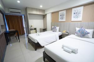 a hotel room with two beds and a desk at The Spring Bangkok in Bangna
