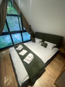 a large bed in a room with a large window at Cabana Casa Luca in Rănuşa