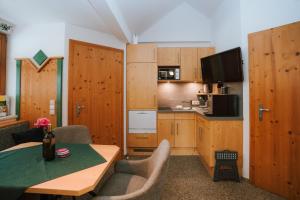 a kitchen with wooden cabinets and a table with chairs at Gästehaus Berger in Tröpolach