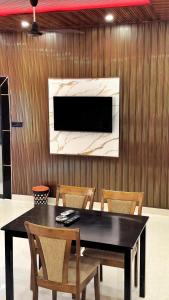 a dining room table with chairs and a television on a wall at Sand Dunes Stay in Bagru