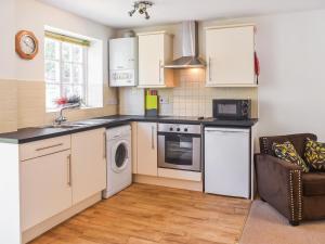 a kitchen with white cabinets and a washer and dryer at Coops Nest in Stalham