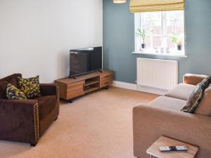 a living room with a couch and a tv at Coops Nest in Stalham