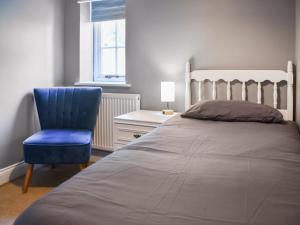 a bedroom with a bed and a blue chair at Coops Nest in Stalham +10 photos