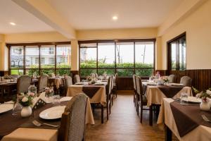 a dining room with tables and chairs and windows at Sparrow Chiminda A-Heritage Hotel Middle Pelling in Pelling