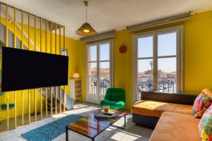 a living room with yellow walls and a flat screen tv at Le Duplex des Halles-Balcon & Clim in Sète