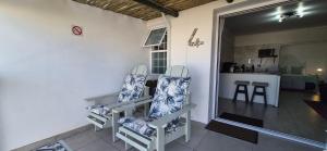 a living room with two chairs and a kitchen at Allview Selfcatering Apartments Jacobsbaai in Jacobs Bay