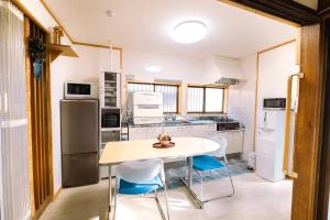 a kitchen with a table and chairs in a room at 民泊豊久 in Nigō