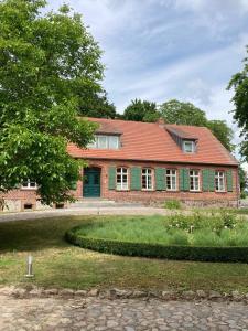a brick house with a green door and a yard at Biohotel Schönhagener Mühle in Pritzwalk