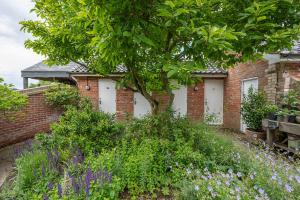 a brick building with white doors and flowers at Toad Hall Lodges - Luxury Glamping Lodges Near Southwold! in Wangford +115 photos