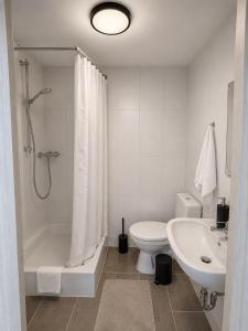 a white bathroom with a toilet and a sink at Schuster's Apartments in Augsburg