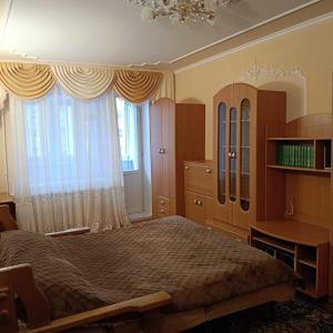 a bedroom with a bed and a desk and windows at Квартира in Sumy
