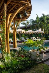 a pool at a resort with tables and chairs at Villa Tokay - The Luxury Resort in Gili Islands