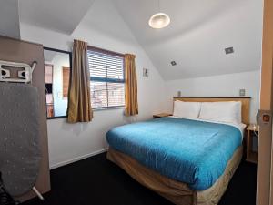 a small bedroom with a bed and a window at Athena Motel in Christchurch