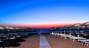 a beach with chairs and umbrellas on the beach at Domus Dafne Apartment in Senigallia