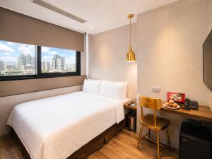 a hotel room with a bed and a desk and a window at Hotel Relax 5 in Taipei