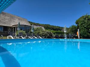 a large blue swimming pool with chairs and umbrellas at La Maraiquaise in Marais-Vernier