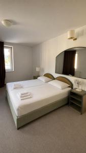 a bedroom with a large white bed and a mirror at Hotel Lucija in Most na Soči +23 photos