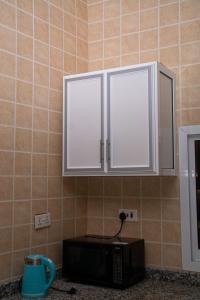 a microwave in a kitchen with white cabinets at Bandari House Malindi in Zanzibar City +21 photos
