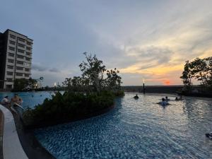 a swimming pool with people in the water at sunset at Rumah Suri Homestay at Arena2 Residence Kota Warisan in Sepang