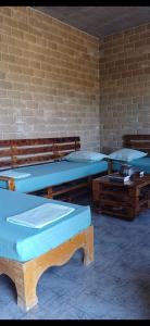 a room with three beds and benches and a brick wall at Caslune in El Bidha