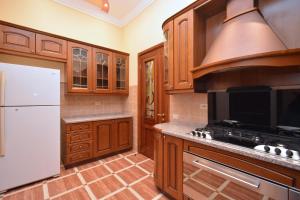 a kitchen with wooden cabinets and a white refrigerator at Tumanyan Guesthouses in Yerevan