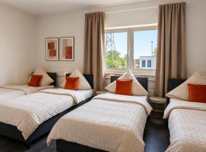 three beds in a room with a window at BASE stay Erlangen in Erlangen