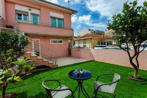 a patio with a table and chairs on a lawn at Alegria Beach House in Vila do Conde