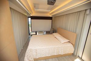 a small bedroom with a bed and a projector screen at Mars Oasis Capsule in Charnali