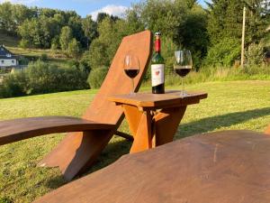 a wooden bench with a bottle of wine and two glasses at Apartment far away from Africa in Steinach